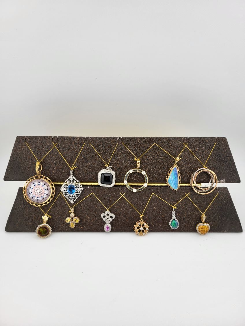 Jewelry display featuring various pendant necklaces with gold chains, arranged on a brown stand.