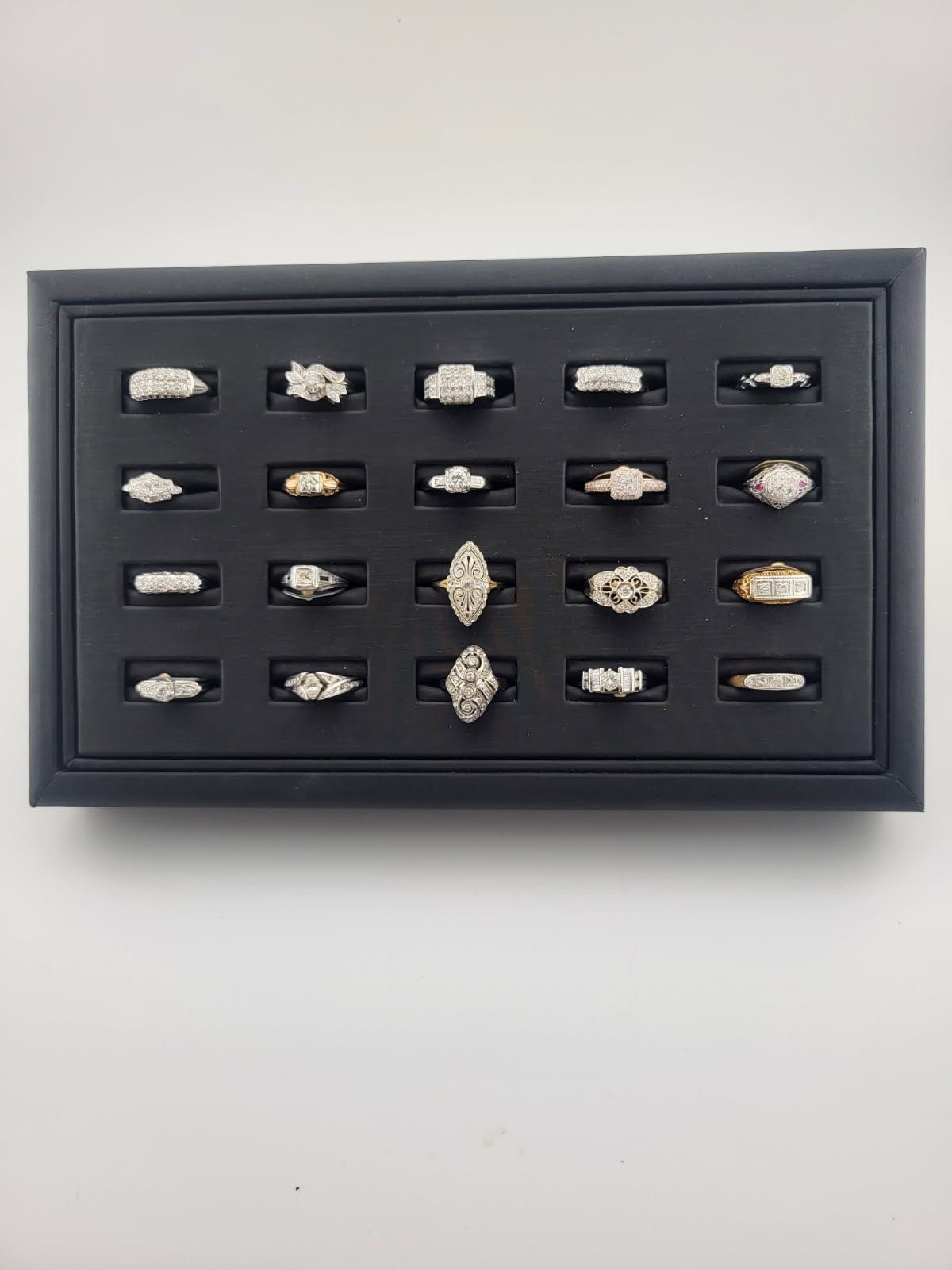 Black tray with multiple diamond rings displayed.