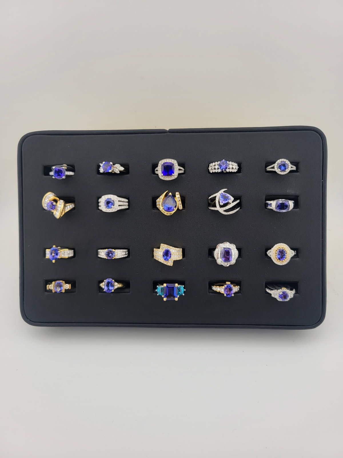Black tray filled with 24 sapphire rings on display.