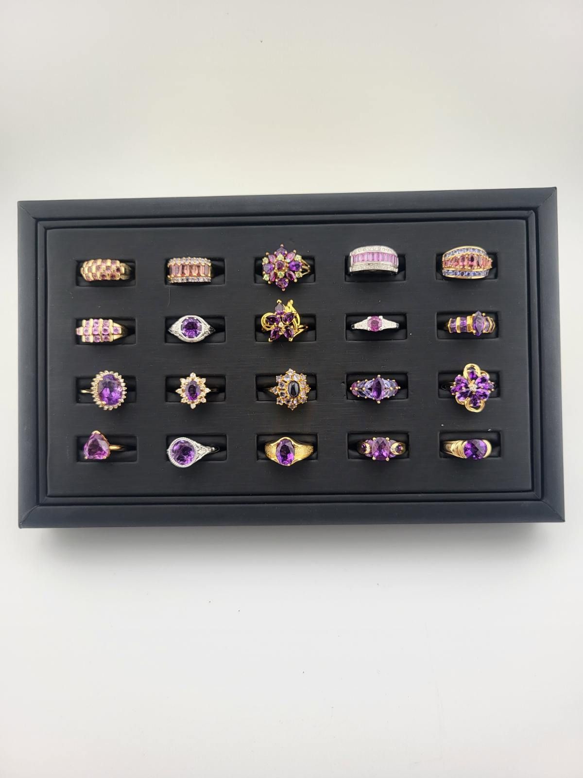 Black display tray filled with various amethyst rings.