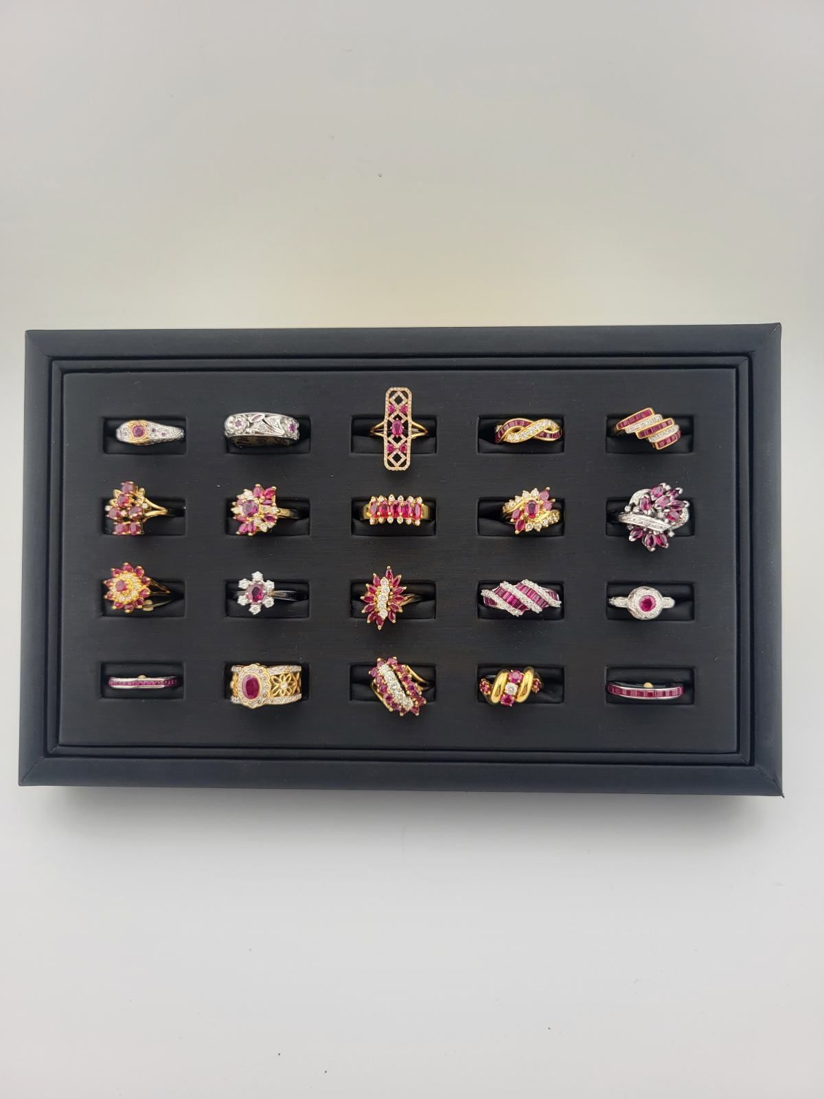 Black display case filled with gold rings, many with ruby-colored stones.