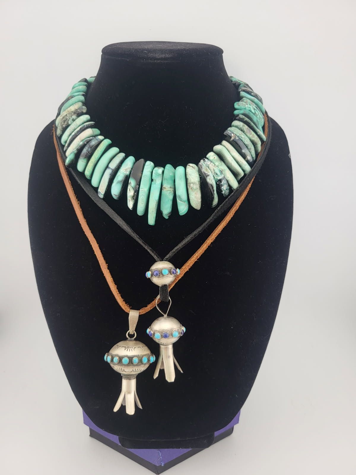 Turquoise and silver necklaces displayed on a black mannequin.