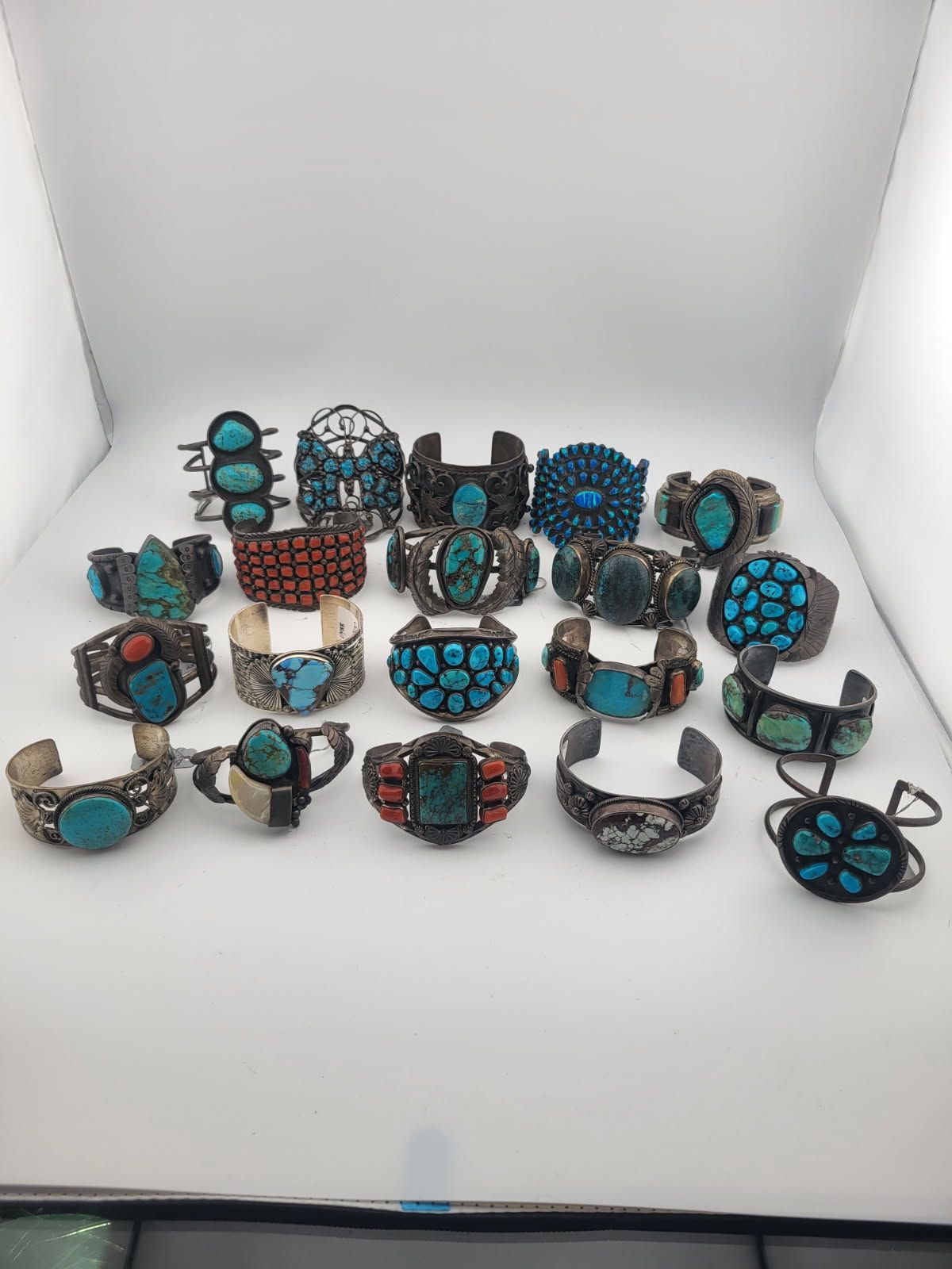 Collection of silver bracelets with turquoise and coral stones on a white background.