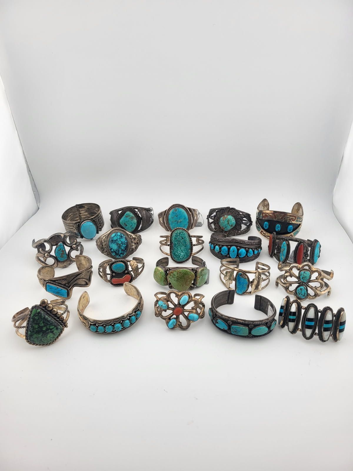 Group of turquoise and silver bracelets on a white surface.
