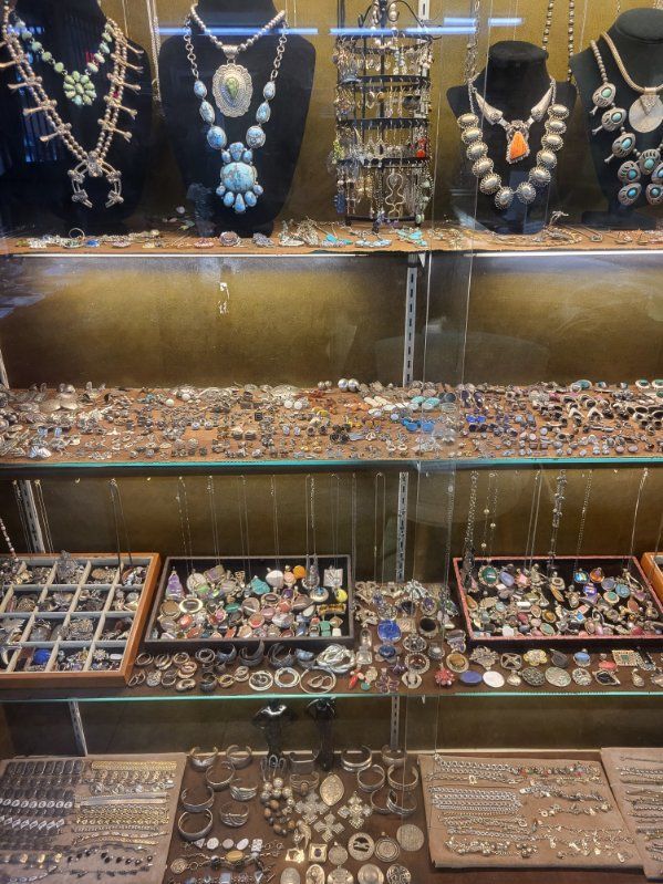 Jewelry display case filled with necklaces, rings, and earrings, showcasing turquoise and silver.