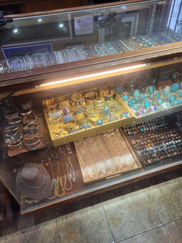 Jewelry display case filled with bracelets, rings, and necklaces, lit by an overhead light.