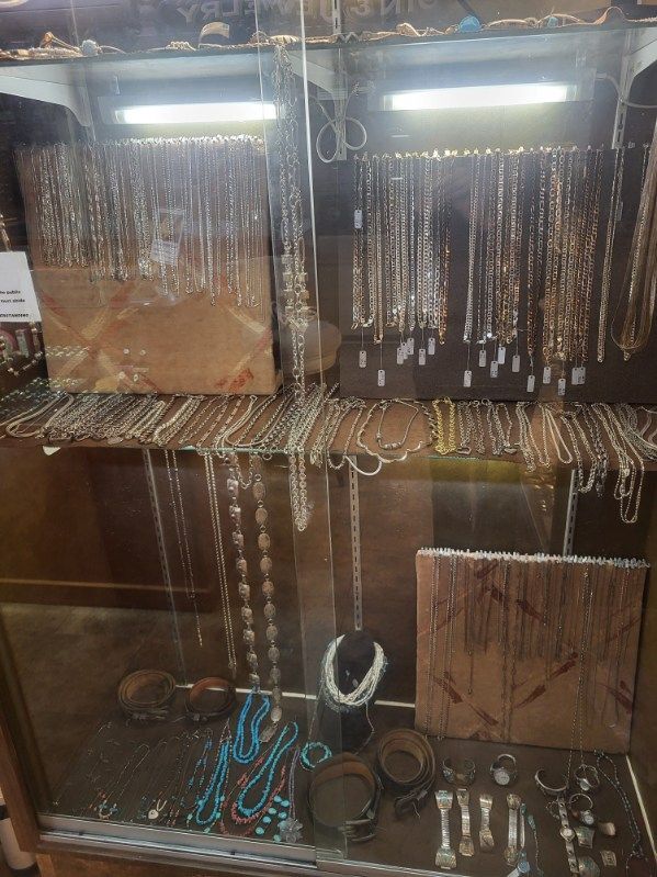 Jewelry display case filled with necklaces, bracelets, and other silver-toned items.