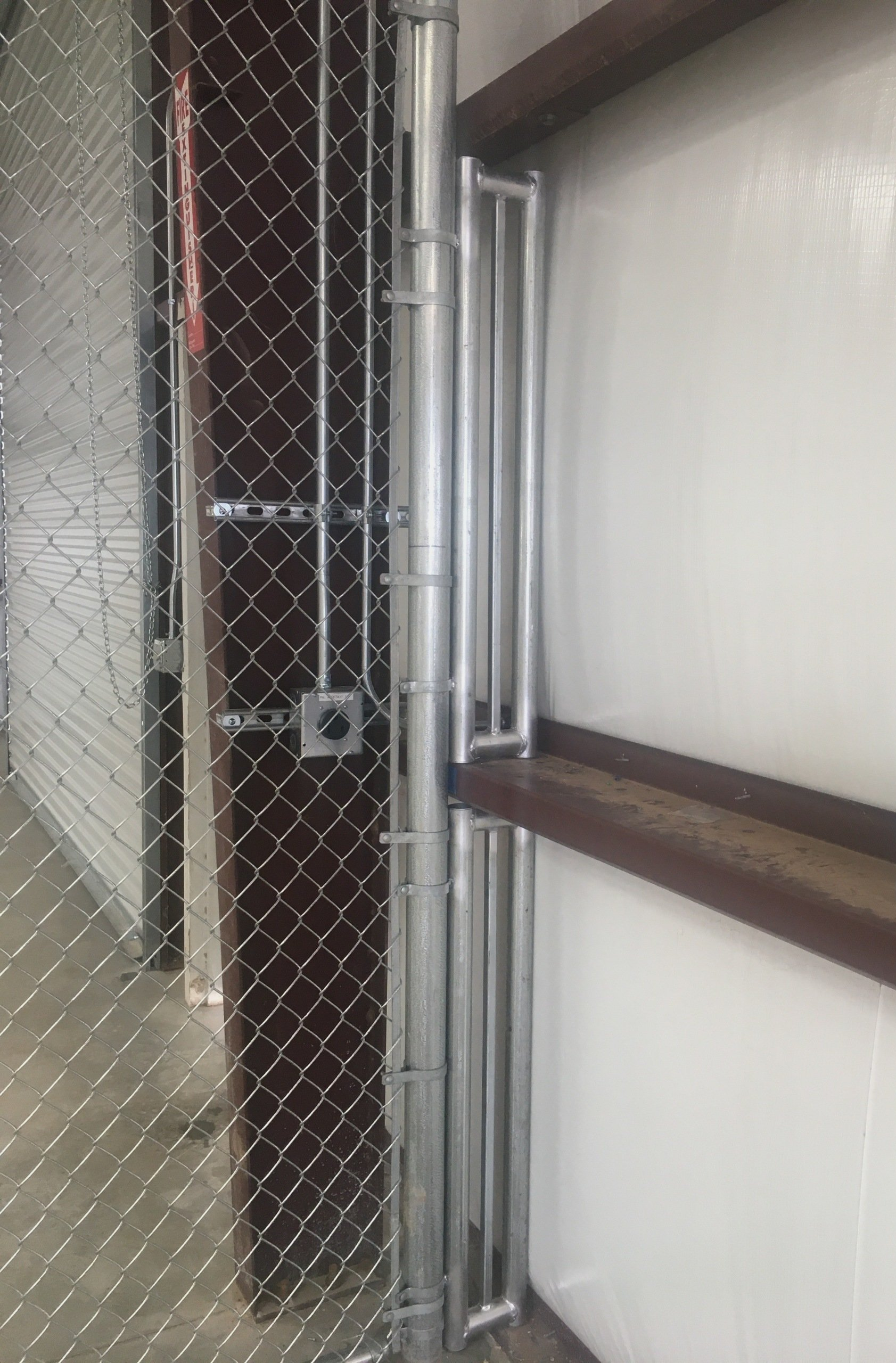 Chain-link fence with a metal gate and door. The door is dark brown.