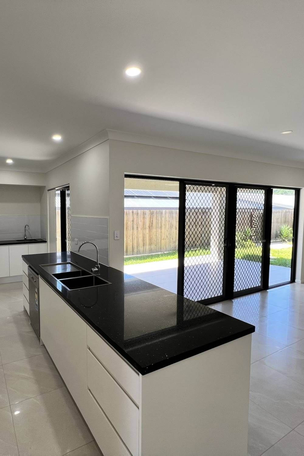 A Large Empty Room With A Ceiling Fan And Sliding Glass Doors — Rental Revolution In Manoora, QLD