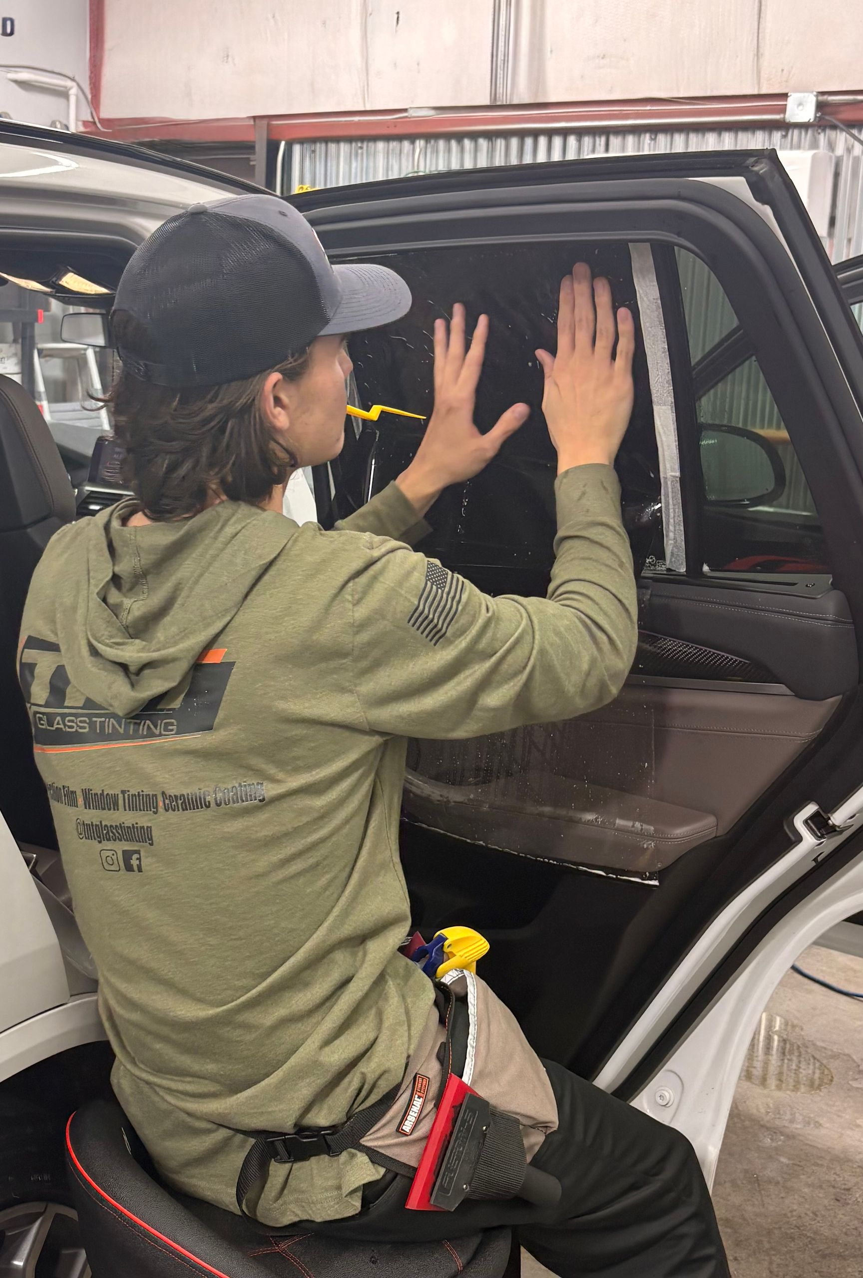 A light blue, vintage two-door hardtop convertible parked on an asphalt lot in front of a tan metal warehouse.