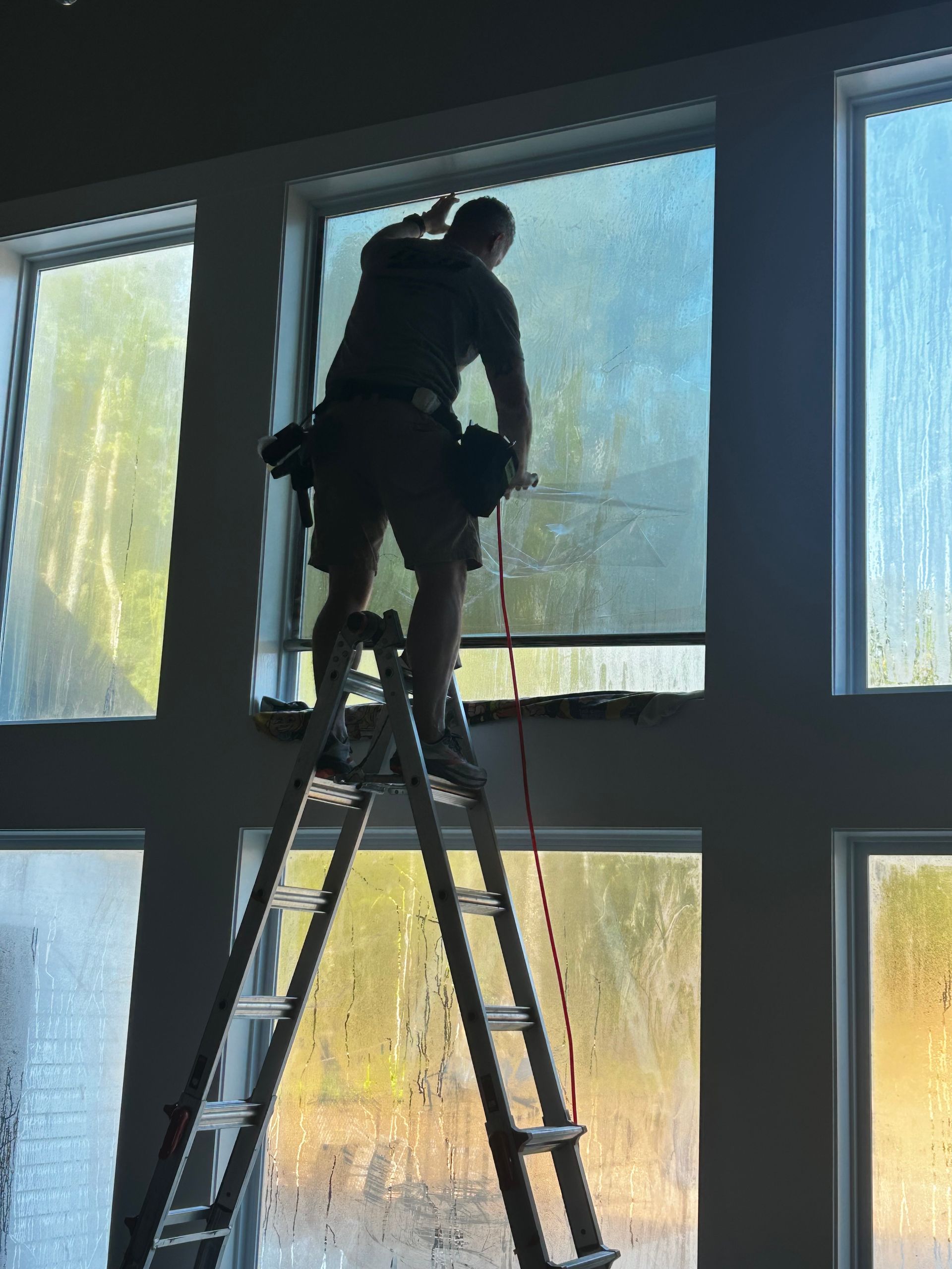 Shower interior with white marble-style tiled walls, a square window with privacy glass, and a built-in shampoo niche.