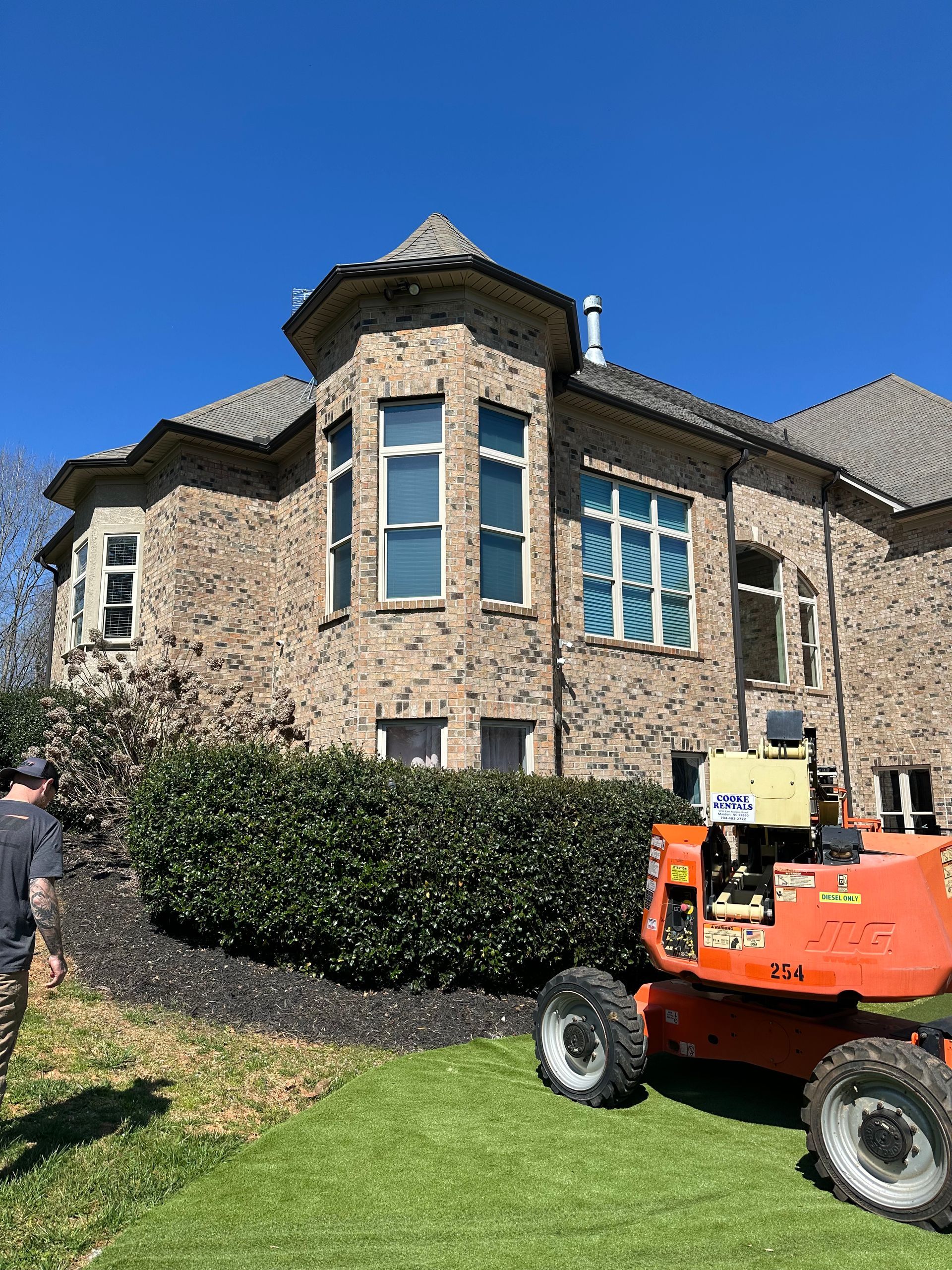 A patio area with outdoor tables and metal chairs, viewed from inside through a window divided by a vertical wooden post.