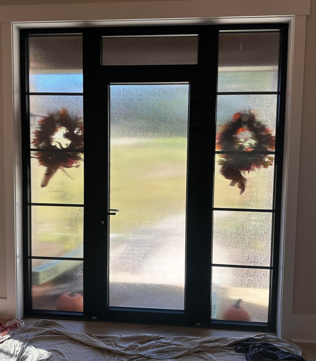 A set of double doors, one with frosted glass and one with clear glass, looking out onto a wooded yard.