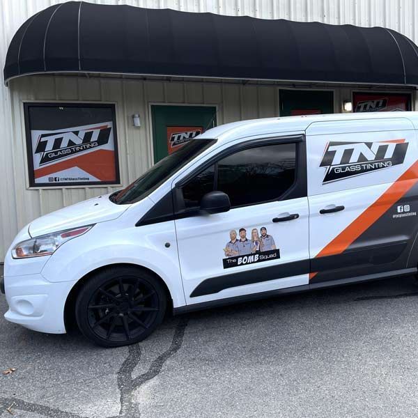 A white sports car is parked in front of a tnt trailer