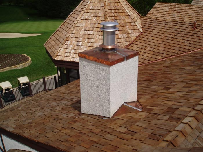 A chimney on top of a wooden roof with a golf course in the background