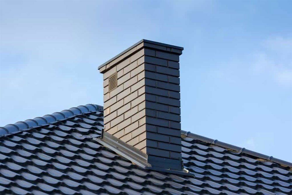 A chimney is sitting on top of a tiled roof.