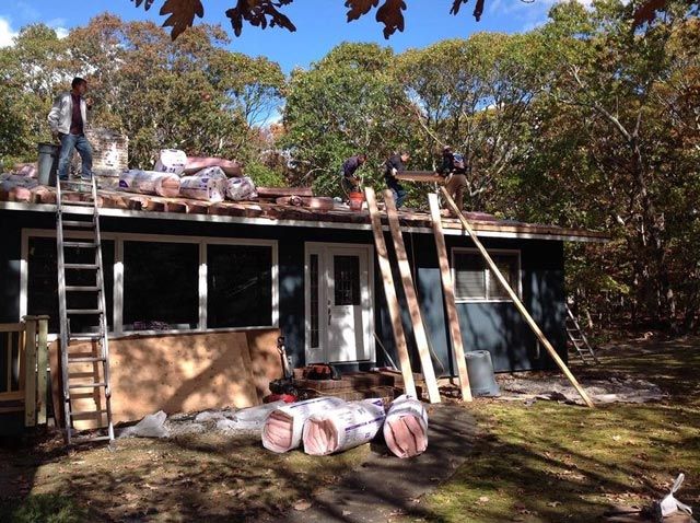 A group of people are working on the roof of a house
