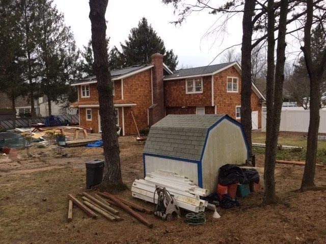 A shed sits in front of a house under construction