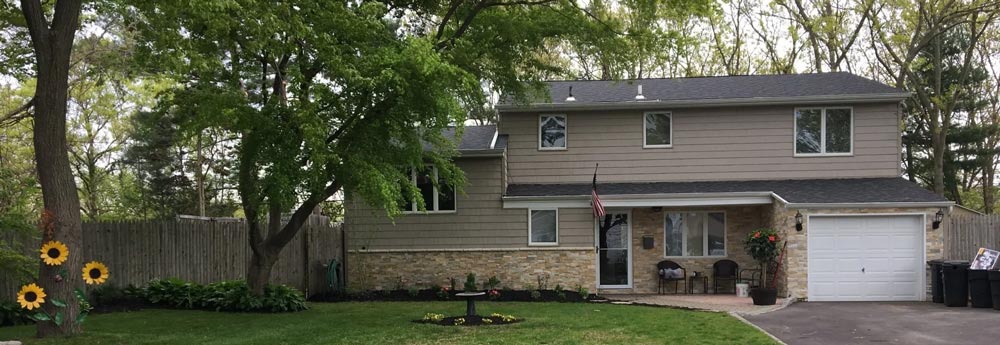 A house with a garage and a tree in front of it