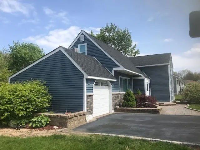 A blue house with a white garage door and a driveway.