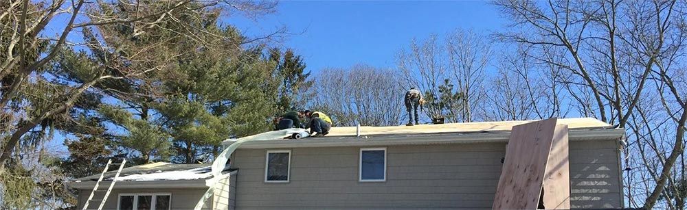 A group of people are working on the roof of a house.