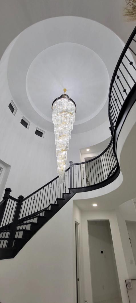 A spiral staircase with a chandelier hanging from the ceiling.