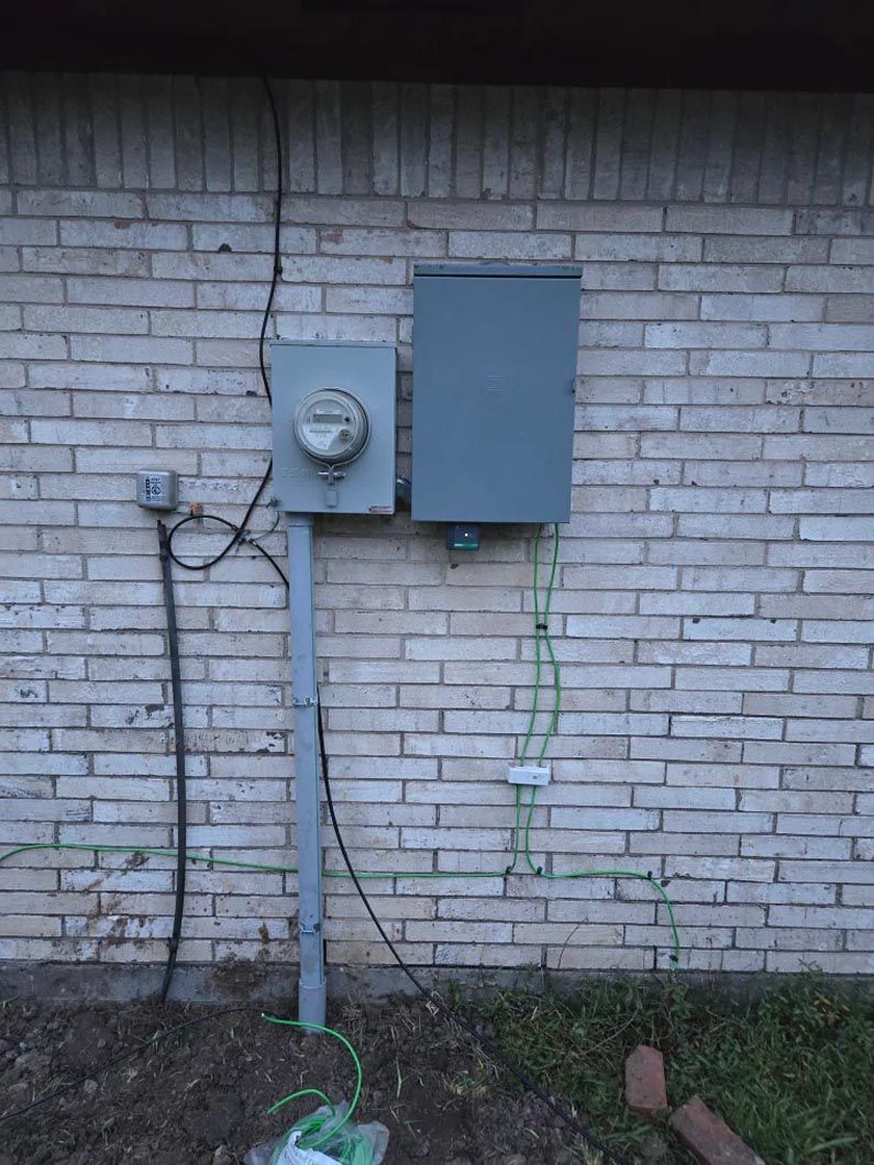 A brick wall with a meter and a box on it.