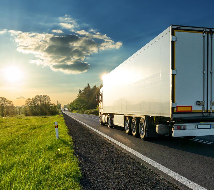 Hazy afternoon photo of river and bridge in Cambridge. Punt boat in middle-distance. Trees either side.