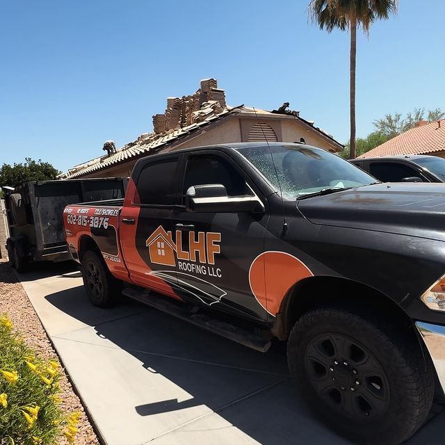A roofing company truck is parked in front of a house