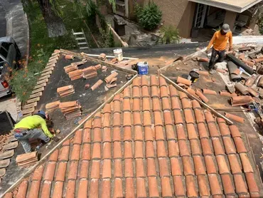 A group of men are working on a tiled roof.