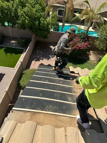 Two men are working on the roof of a house.