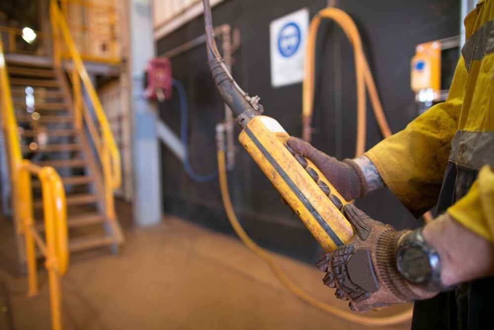 A Man In A Yellow Shirt Is Holding A Yellow Object In His Hands — Bastion Electrical In Wollongong, NSW

