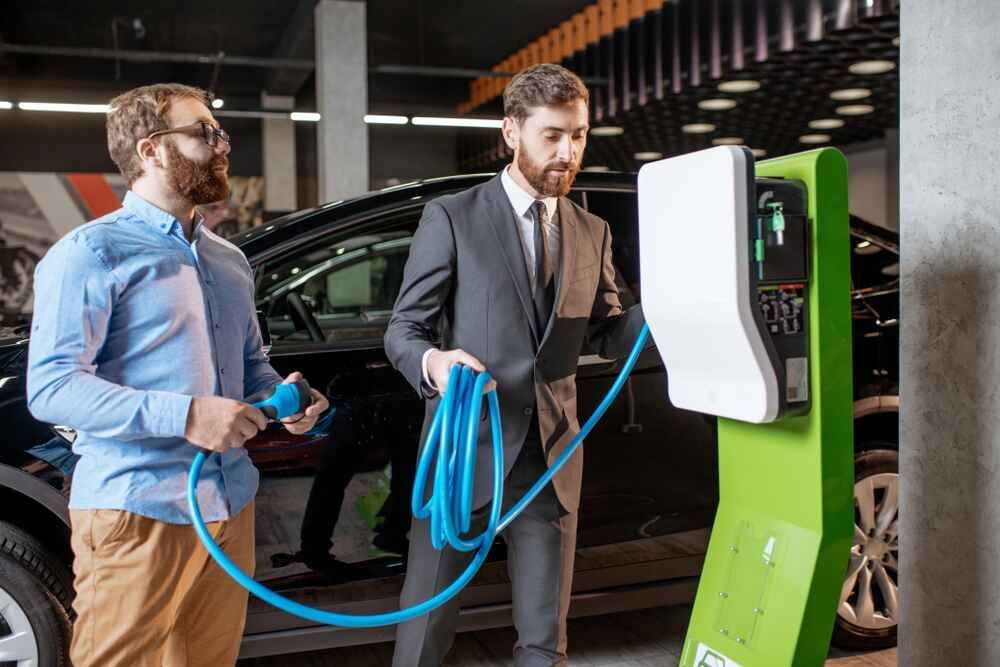 Two Men Are Charging An Electric Car At A Charging Station — Bastion Electrical In Wollongong, NSW
