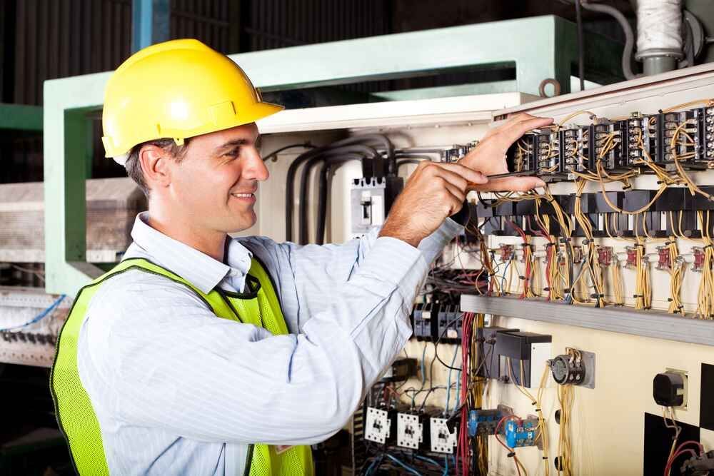 A Man Wearing A Hard Hat And Safety Vest Is Working On A Machine — Bastion Electrical In Cordeaux Heights, NSW