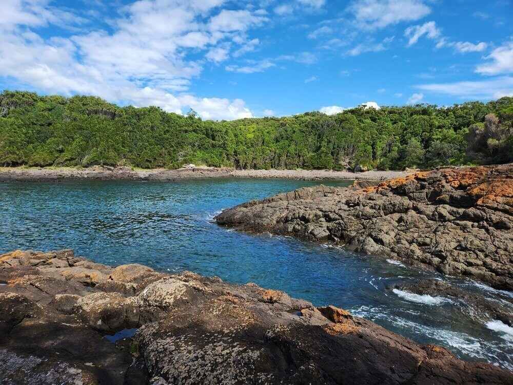A Large Body Of Water Surrounded By Rocks And Trees On A Sunny Day — Bastion Electrical In Shellharbour, NSW