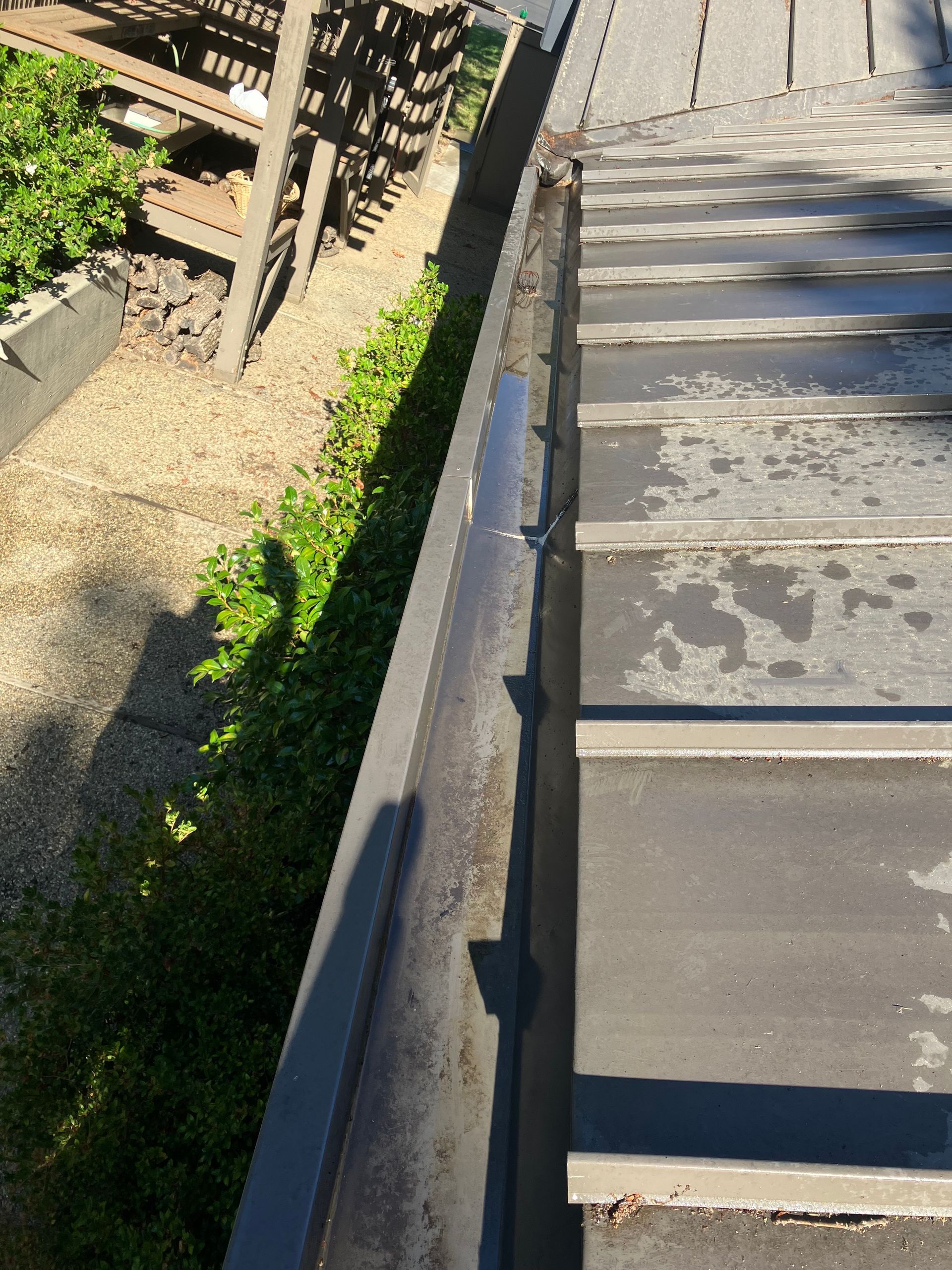 Gutter next to a dark roof; a small garden and gravel on the left.