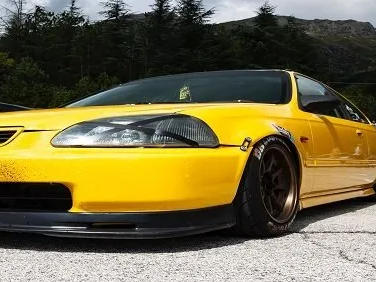 Yellow Honda Civic coupe with black accents, parked outdoors.