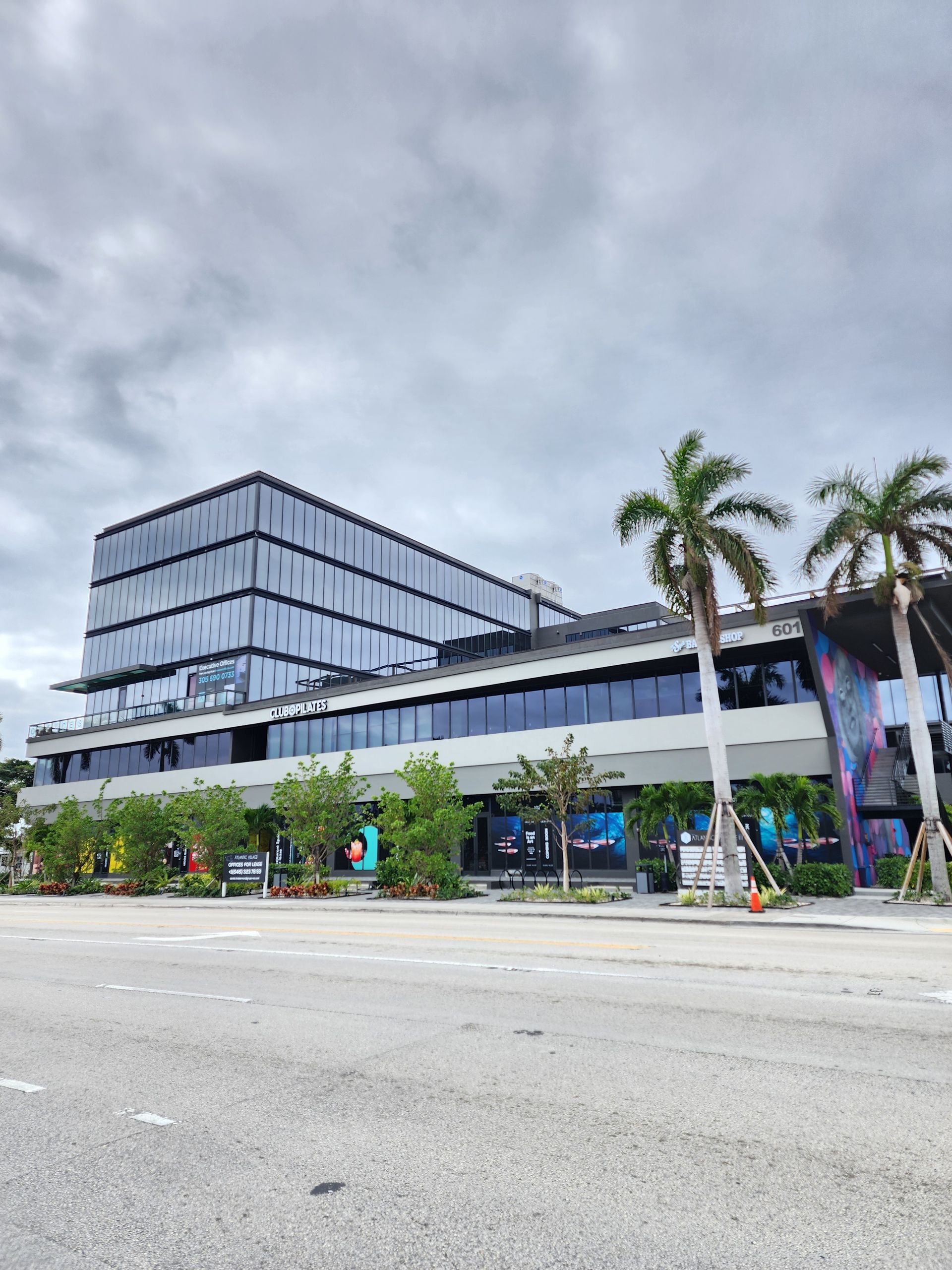 Un gran edificio con palmeras delante en un dรญa nublado.