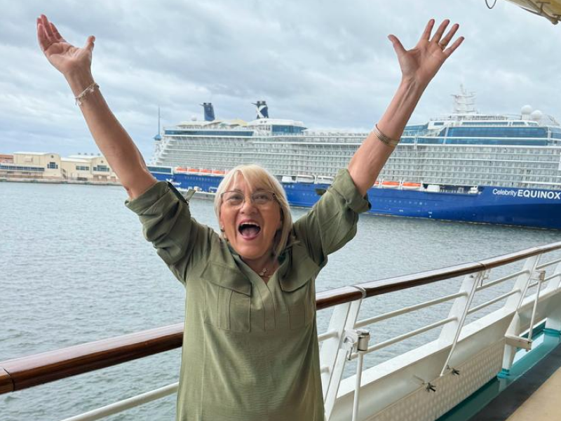 Una mujer está parada en un crucero con los brazos en el aire.