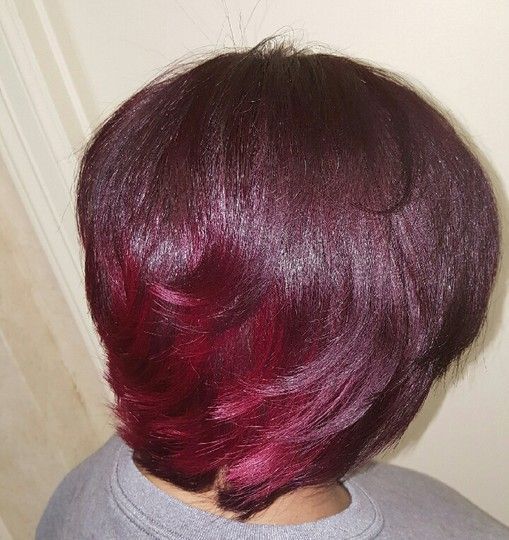 Woman with a bob haircut, dark red on top, with a vibrant red ombre effect at the ends.