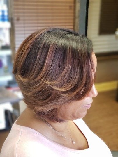 Woman with layered bob, dark roots, and auburn highlights; indoors.