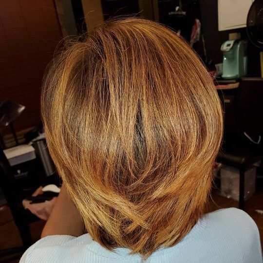 Blonde layered bob haircut. Highlights of blonde and brown hair. Inside a salon.