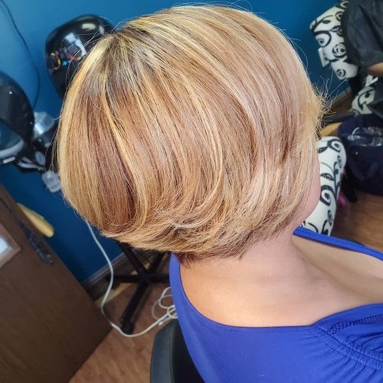 Woman with short, layered blonde hair highlighted with reddish-brown tones, wearing a blue top.