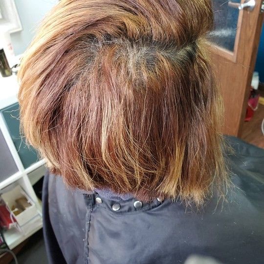 Woman's short, layered brown hair with blonde highlights, seen from the back.