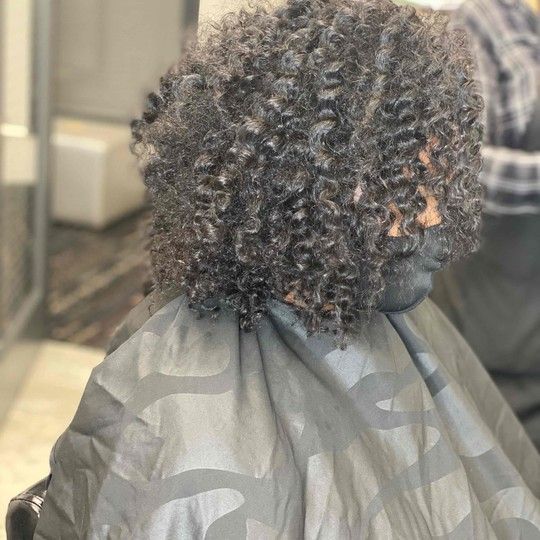 Hairdresser applying treatment to client's wet hair in a salon.