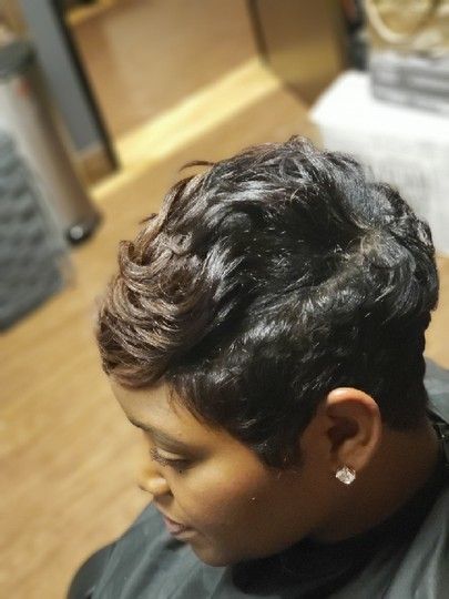 Woman with a short, wavy, dark brown pixie cut hairstyle; indoors.