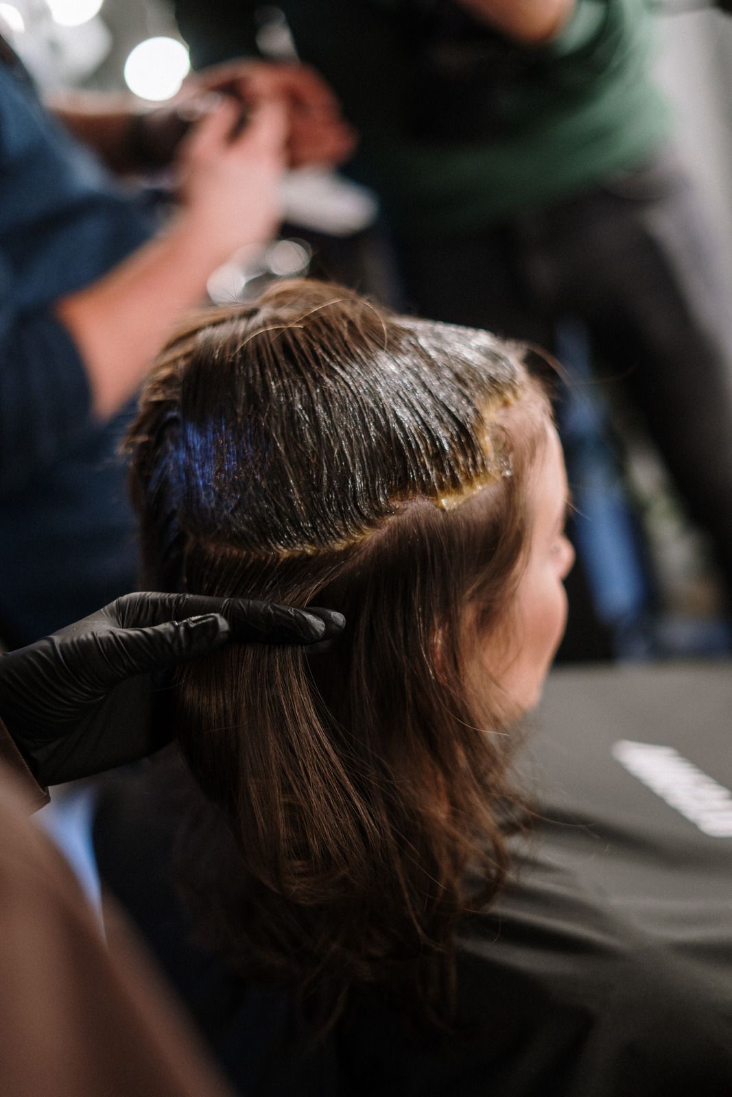 Hairdresser applying hair dye to a client's hair in a salon.