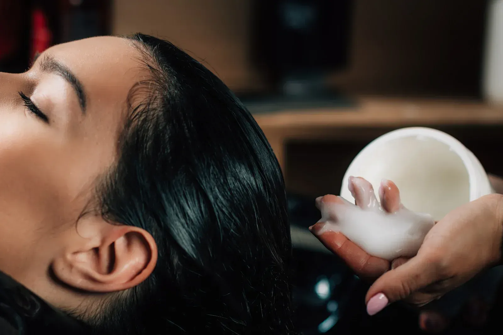 Woman getting her hair washed with white foam at a salon.