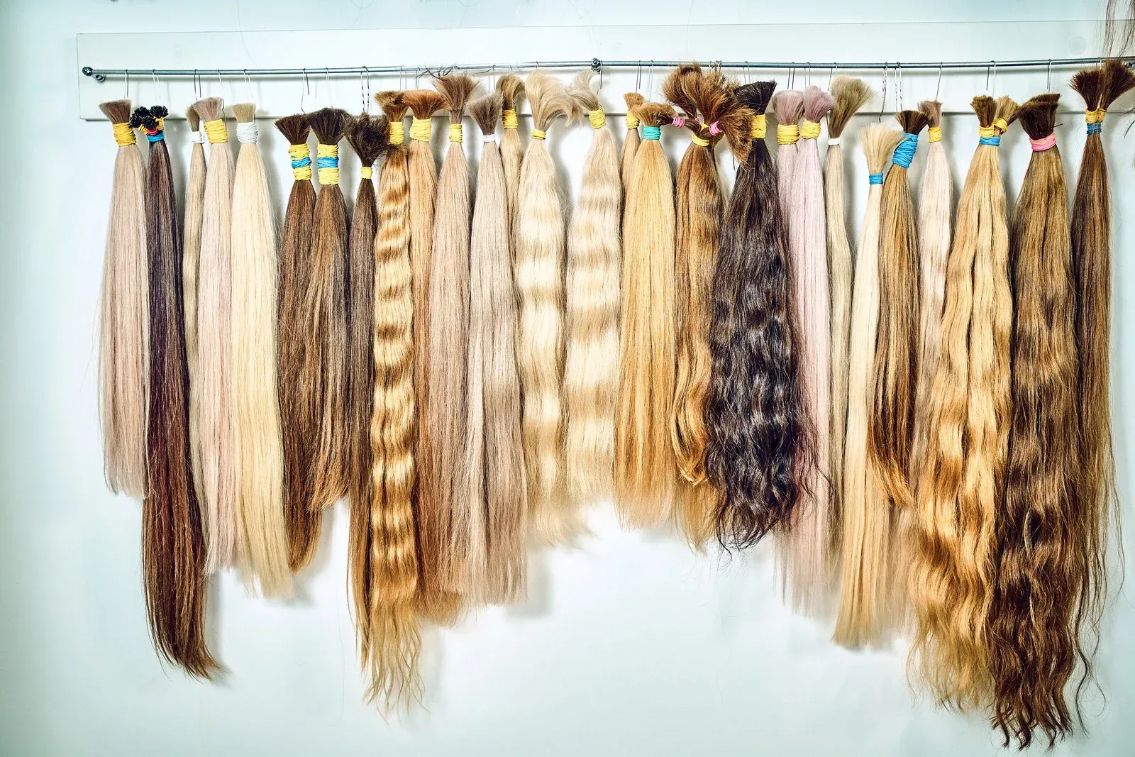 Bundles of human hair in various shades, hanging on a rack.
