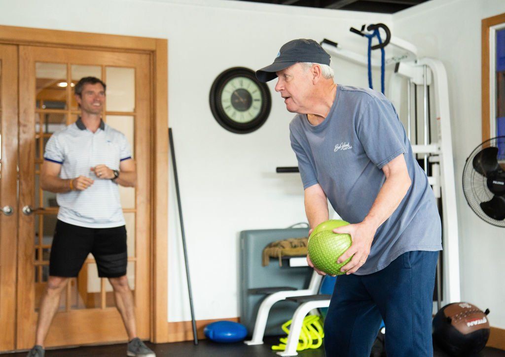A man is throwing a ball in a gym while another man watches.